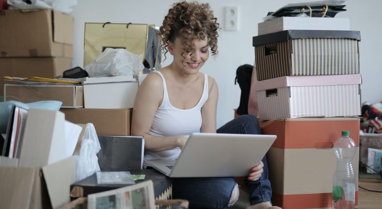 Female student using a laptop surrounded by packing boxes